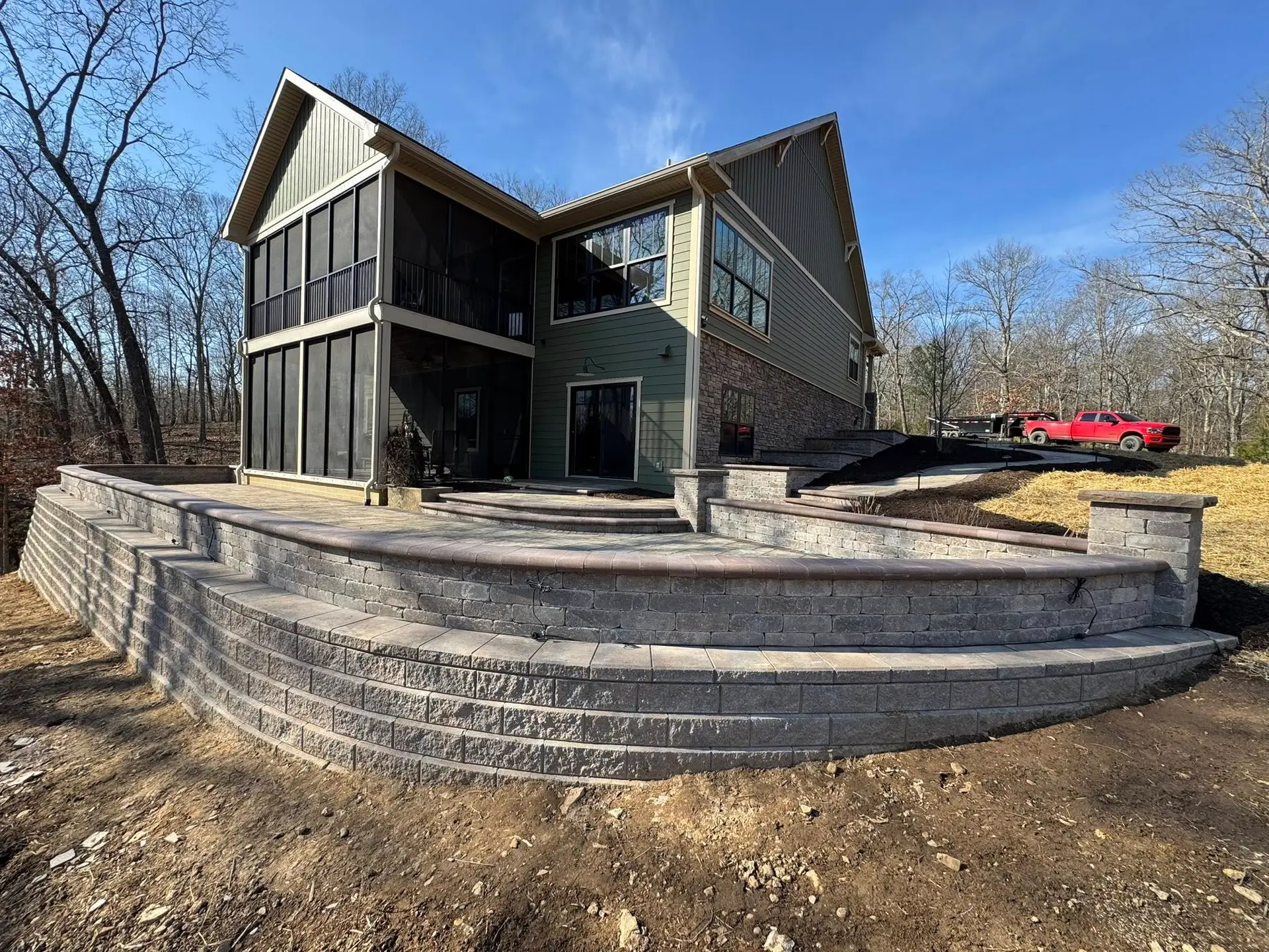 Stacked stone retaining wall and curbing built into a hillside by The Muscle