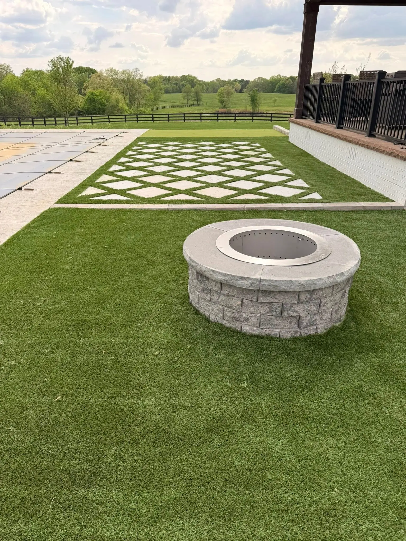 Backyard fire pit and stone patio at dusk — a recent installation by The Muscle