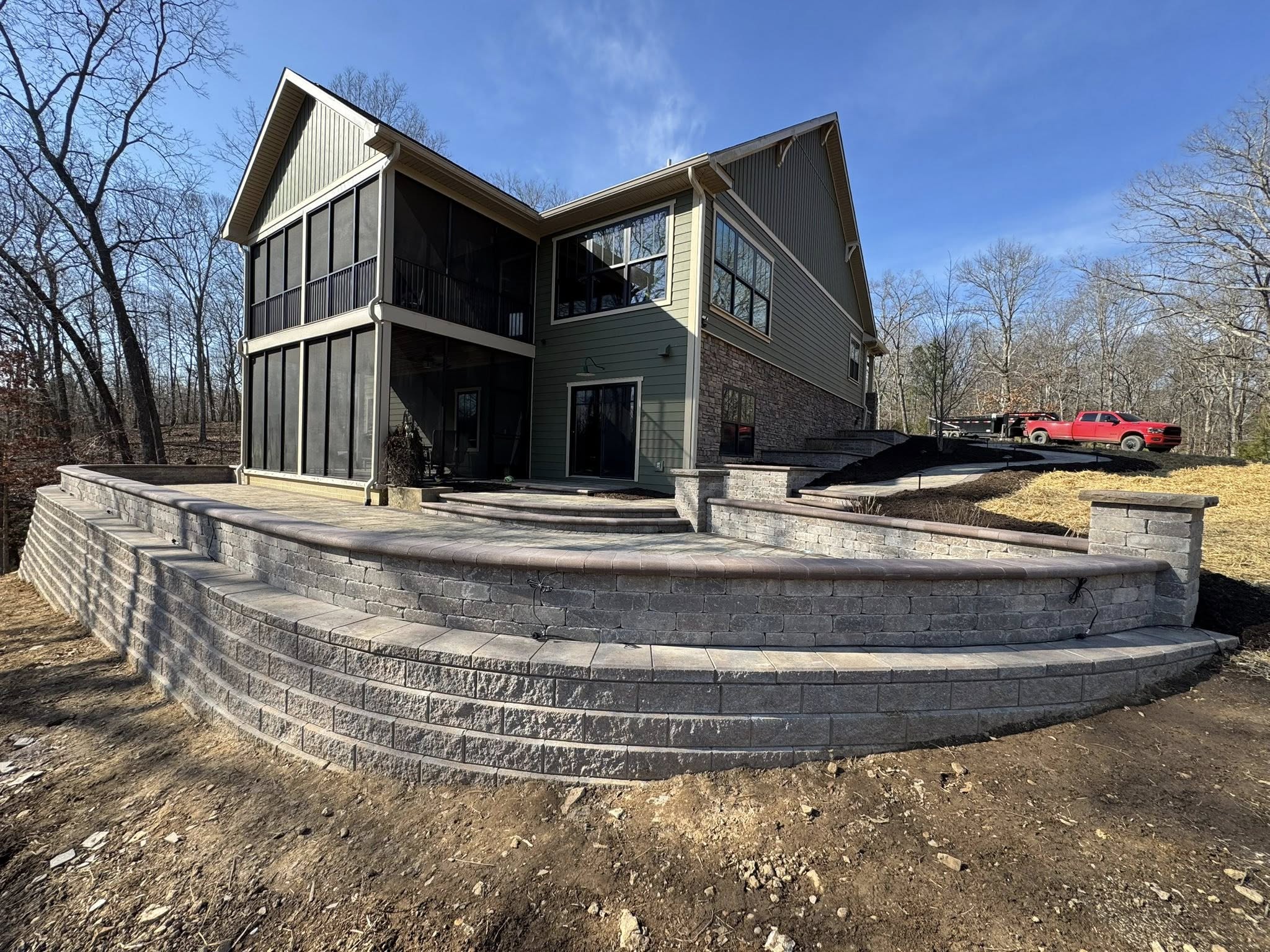 Stacked stone retaining wall and curbing built into a hillside by The Muscle
