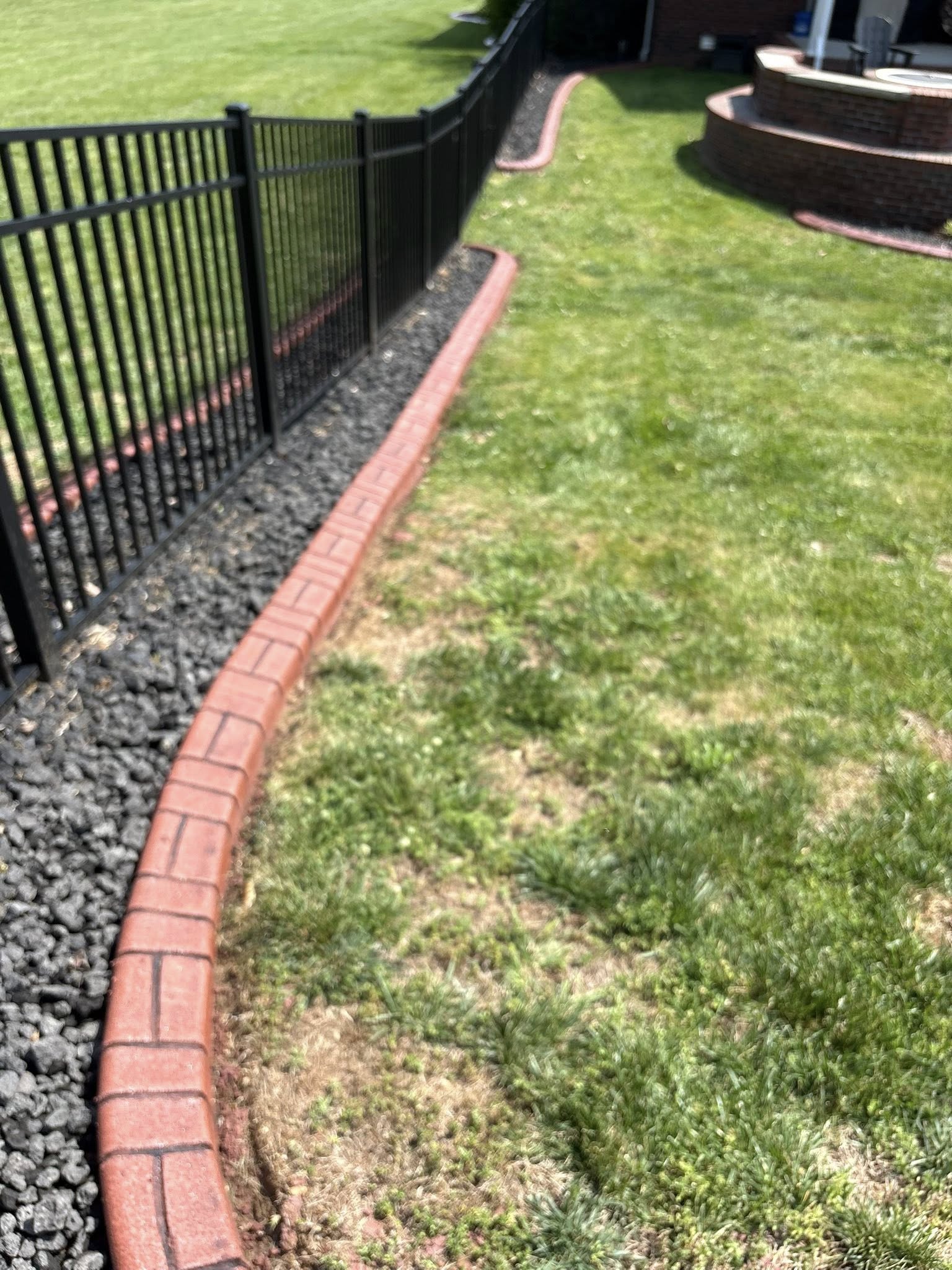 Stamped concrete curbing wrapping around a residential flower bed